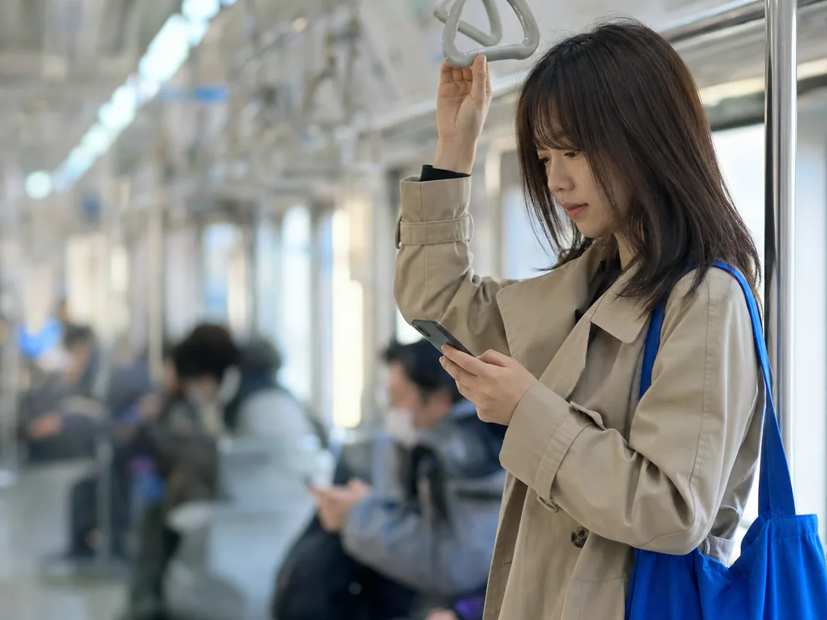 출근길 지하철에서 손잡이를 잡고 휴대폰으로 영단어를 넘기는 직장인